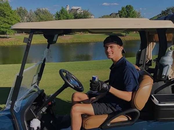 Collin Brientnall riding a golf car 